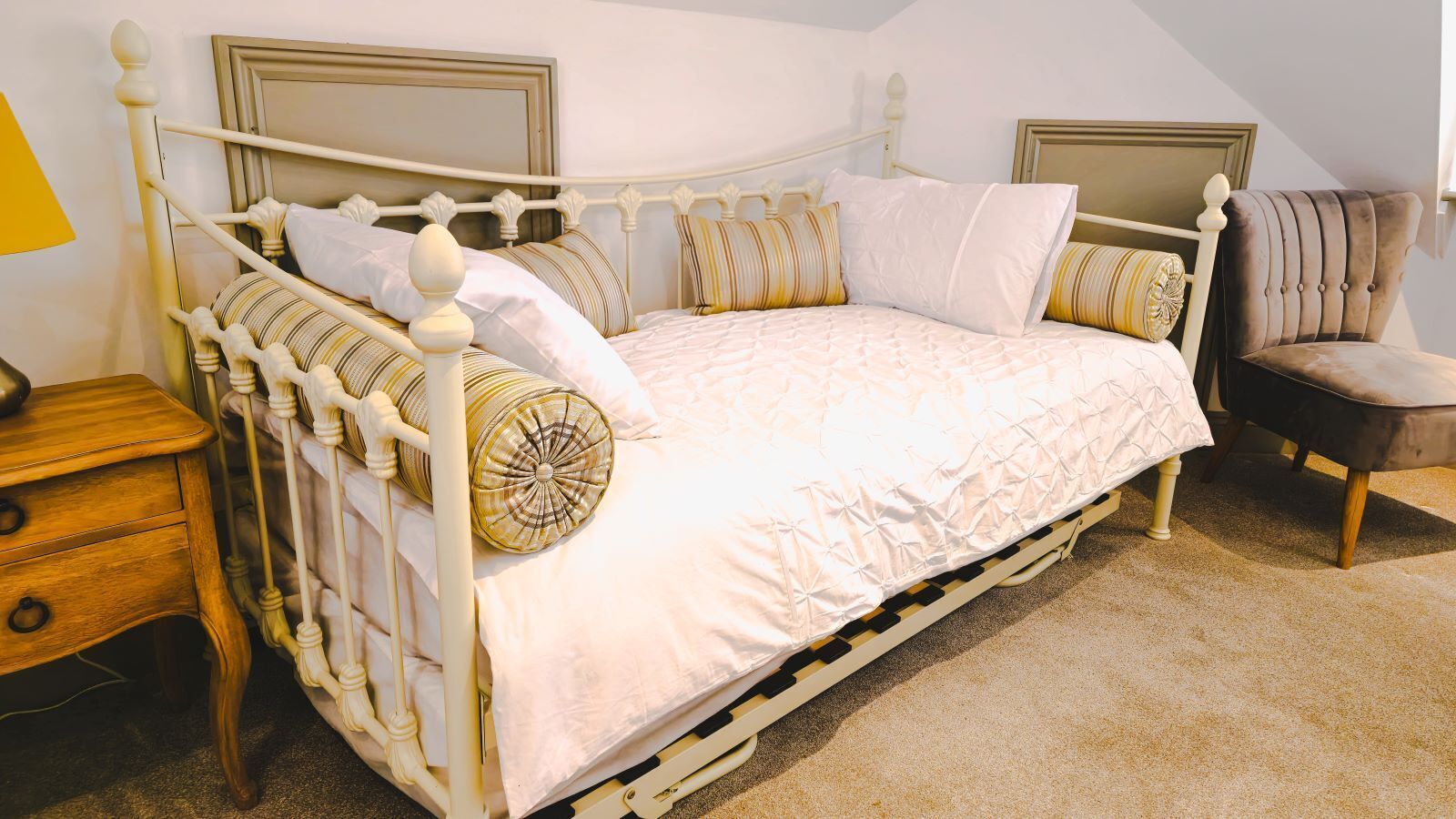 Een hemelbed met een wit frame en een beigekleurige vloerbedekking.