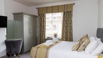 A hotel room with a bed, a wardrobe, a desk, and a window with curtains.