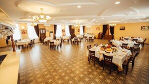 Un comedor amplio con múltiples mesas y sillas, elegantes candelabros y piso con diseño.