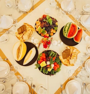 Une table dressée pour un repas, avec différents plats, notamment des fruits, des légumes et du pain.