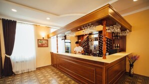 Zona de bar con mostrador de madera, botellas de vino y copas.