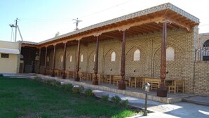 Un edificio con zona de estar al aire libre techada, columnas de madera y fachada de ladrillo.