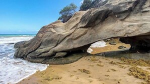 A natural rock formation with a lighthouse on top, overlooking a beach with waves. - Perla del Mar | Perfect Beach Escape (Maunabo)