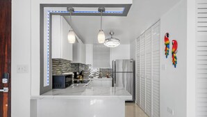 A modern kitchen with a central island, pendant lights, and a refrigerator. - Perla del Mar | Perfect Beach Escape (Maunabo)