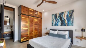 Une chambre à coucher avec un lit, une armoire en bois, un ventilateur de plafond, un tableau et une table de chevet.