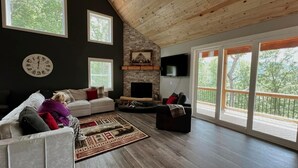 Un salon spacieux doté d’une cheminée, de grandes fenêtres et d’un coin salon confortable.