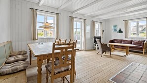 Ein geräumiges Zimmer mit einem Holzespeisetisch, Stühlen, einer Couch und einem Fernseher.