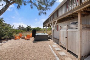 Un espace extérieur abrité comprenant un jacuzzi, des chaises orange et une terrasse en bois.