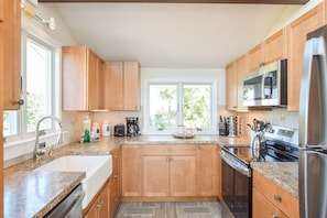 Une cuisine avec des meubles de rangement en bois, un réfrigérateur en acier inoxydable, un four à micro-ondes et une machine à café.