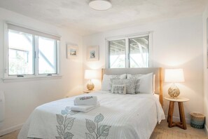 A bedroom with a bed, two bedside lamps, a window, and a wall-mounted picture. - Hot Tub, Waterfront Home with Stunning Views! (Wellfleet)