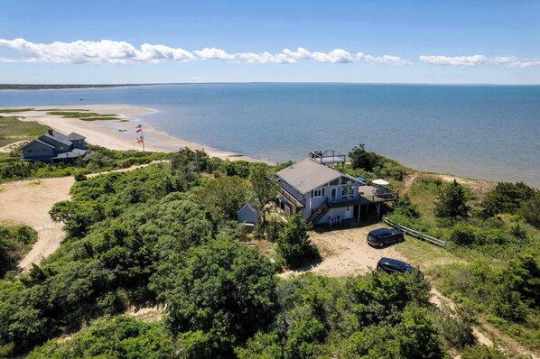 Une propriété située sur la côte, comprenant une grande maison, une plage et une vue sur la mer.