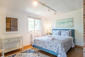 Un dormitorio con cama, escritorio, ventana y radiador.