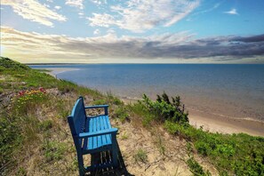 Un banc bleu donnant sur une plage, avec vue sur l’océan et un ciel nuageux.