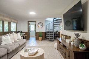 A modern living room with a sofa, coffee table, and a TV mounted on the wall. - Hot Tub, Waterfront Home with Stunning Views! (Wellfleet)