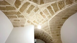 Een kamer met een gewelfd plafond en een bakstenen boogpoort die naar een andere kamer leidt.