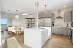 Una cocina moderna con una isla de mármol, armarios grises y vistas al exterior.