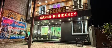 En byggnad med en skylt där det står ”ROOMS GANGA RESIDENCY” och en banderoll som annonserar för ”Conga Fashions”, tillsammans med ett telefonnummer.
