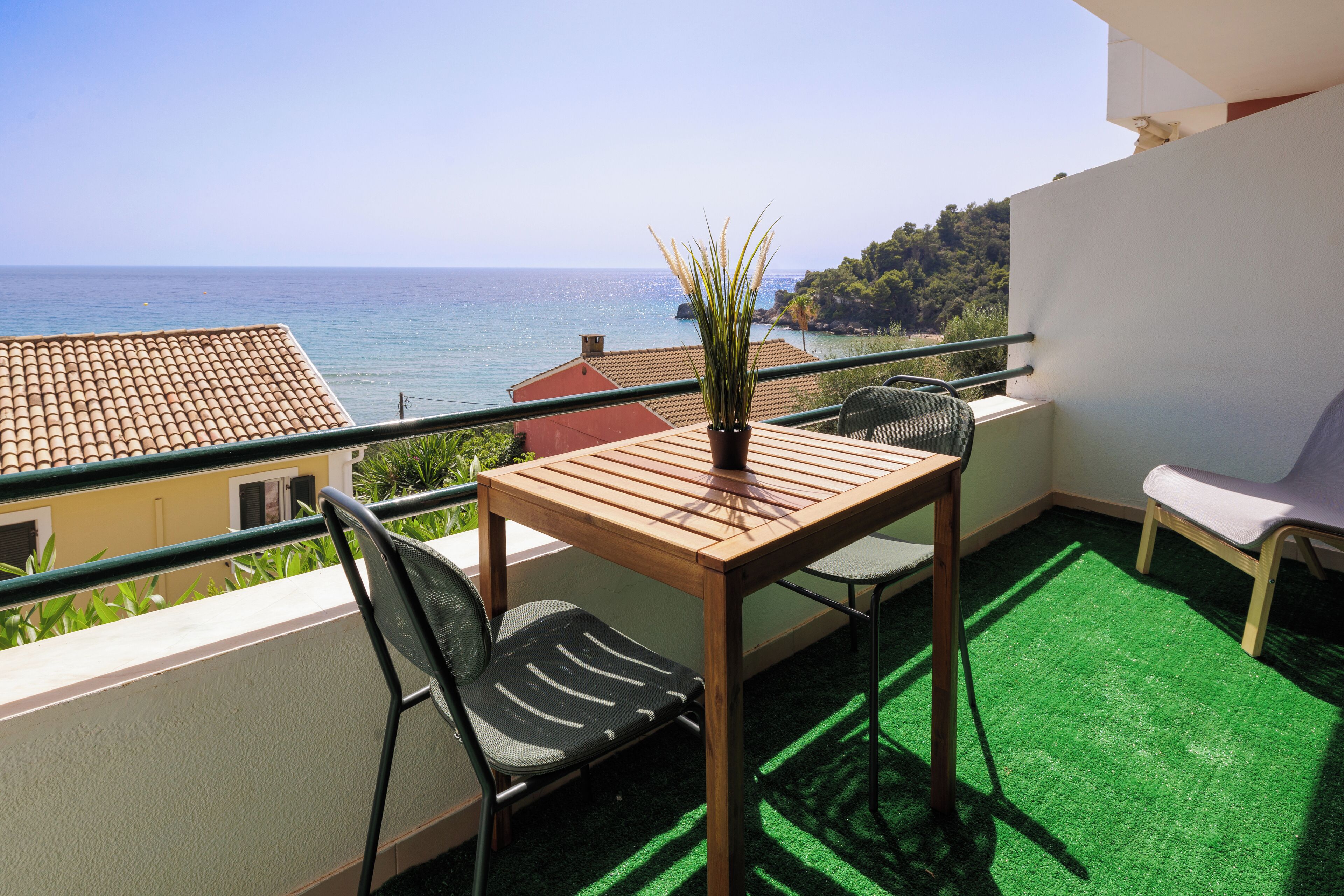 A balcony with a table, chairs, and a potted plant.