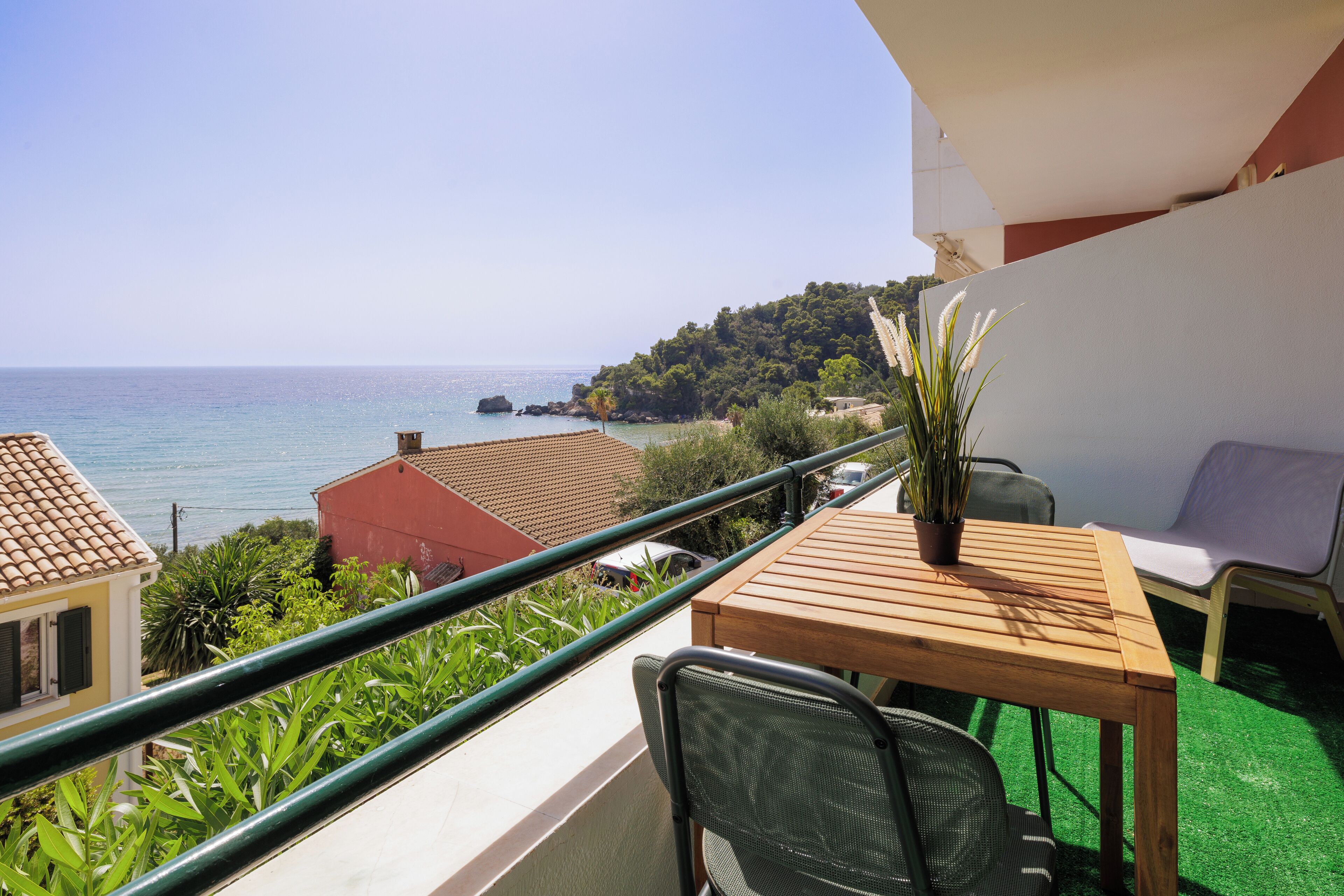 A balcony with a wooden table, a chair, and a potted plant.