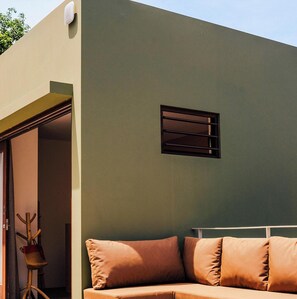 A modern interior with a sofa, a small window, and a door leading to an outdoor area.
