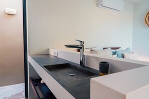 A modern bathroom with a large sink, a faucet, and a towel rack.