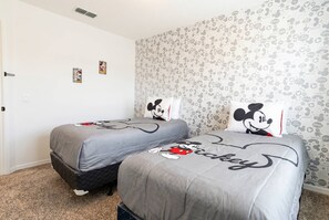 Une chambre avec deux lits, chacun agrémenté de linge de lit aux motifs de Mickey Mouse.