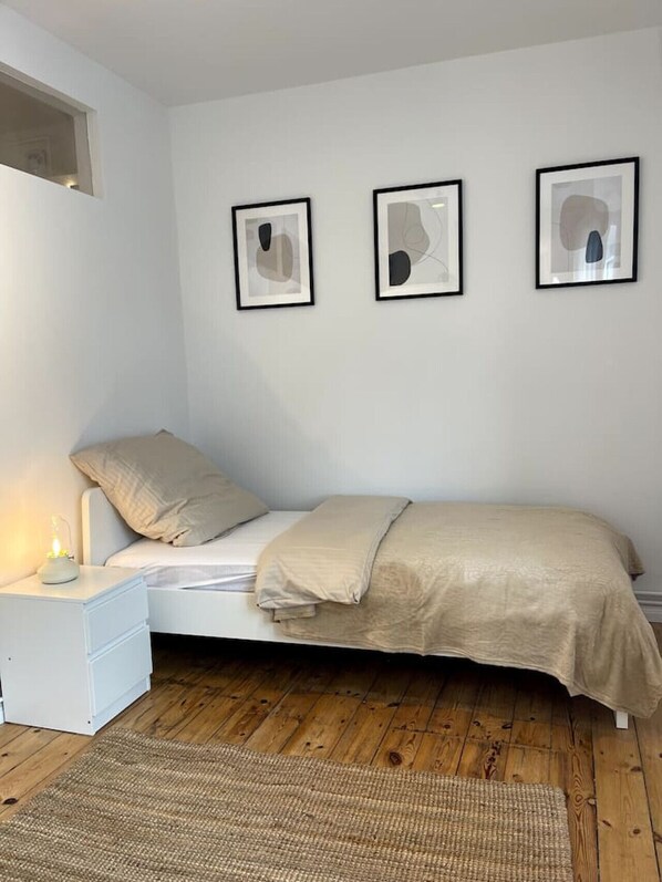 A bedroom with a bed, a nightstand, and three framed abstract artworks on the wall.