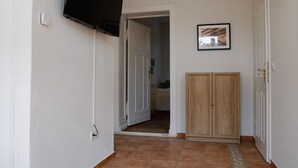 A hallway with a tiled floor, a wooden cabinet, and a door leading to another room.