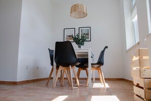 A dining area with a table and four chairs, a pendant light fixture, and a potted plant.
