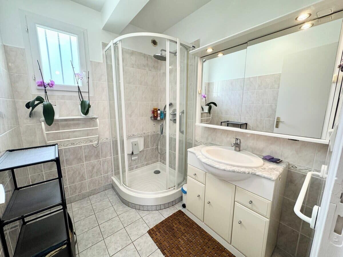 Une salle de bain moderne avec une douche à parois de verre, un lavabo blanc et un grand miroir.