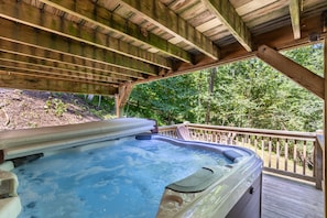 A hot tub under a wooden deck with a view of a forest. - 2 Cubs Cabin (Blowing Rock)