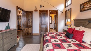 Une chambre avec un grand lit, des portes en bois, une télévision et un petit sapin de Noël.