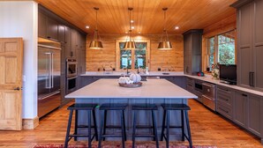 A spacious kitchen with a large island, wooden ceiling, and modern appliances. - A High Country Retreat (Boone)