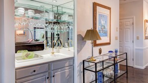 Une salle de bain moderne avec un grand miroir, des étagères en verre et une lampe décorative.