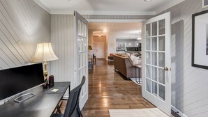 Une cuisine moderne avec des meubles blancs, un coin repas comprenant une table et des chaises, et un couloir menant au salon.