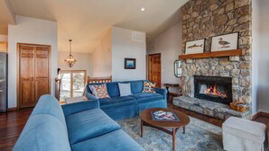 A living room with a stone fireplace, blue sofas, a coffee table, and a stone accent wall. - Hill Station (Banner Elk)