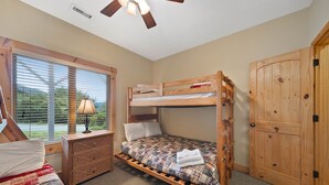 Une chambre avec un lit superposé, une fenêtre, une commode et une armoire.