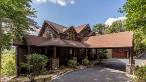 A large, two-story house with a prominent front porch, a garage, and a driveway. - Haven at Headwaters (Elk Park)