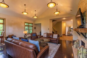A spacious living room with leather sofas, a glass coffee table, and pendant lighting. - Misty Mountain Hop (Blowing Rock)