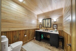 A wooden-paneled bathroom with a toilet, sink, and vanity. - Misty Mountain Hop (Blowing Rock)
