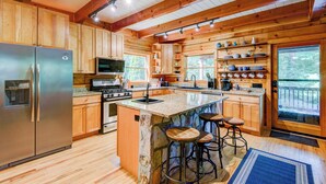 A spacious kitchen with wooden cabinets, a stainless steel refrigerator, a built-in oven, and a large island with bar stools.