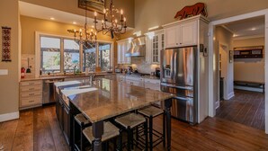 A spacious kitchen with a large island, stainless steel appliances, and a chandelier. - Robin Hoods Retreat (Jefferson)