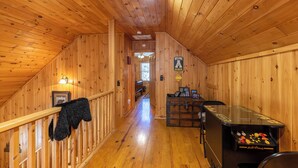 A wooden interior with a wooden staircase, a welcome sign, a billiards table, and a framed picture on the wall. - A Bears Hill (Boone)