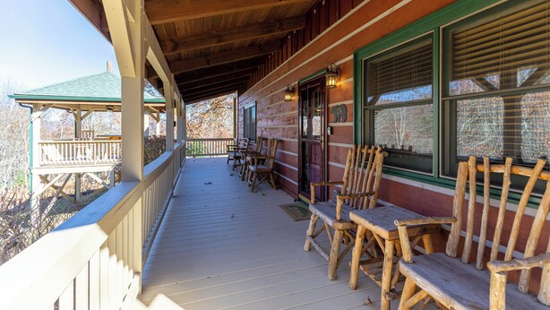 A wooden porch with benches and a covered area, overlooking a forested area. - A Bears Hill (Boone)