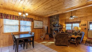 A cozy cabin interior with a dining area, fireplace, and seating. - A Bears Hill (Boone)