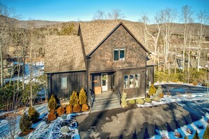 A two-story house with a dark wooden exterior, a gabled roof, and a front porch. - Maynard V at Elk Creek (Banner Elk)