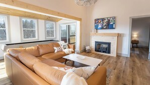 A modern living room with a large sectional sofa, a fireplace, and a television mounted on the wall. - A Red Chalet (Newland)