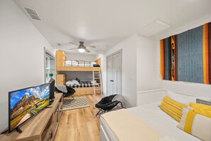 A compact hotel room with a bunk bed, a desk with a computer, a television, and a bed with yellow pillows. - A Red Chalet (Newland)