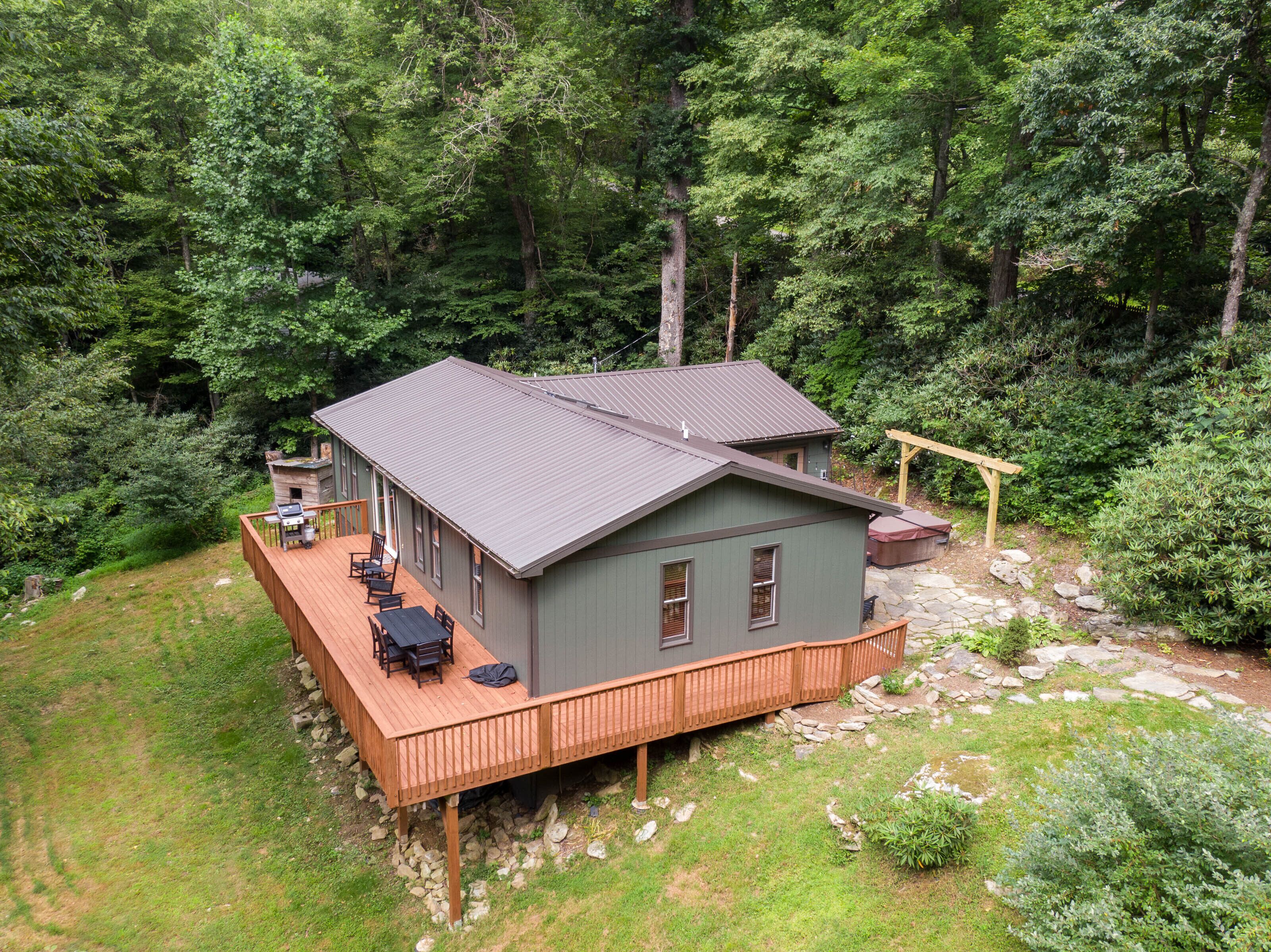A cabin with a deck, surrounded by dense forest.