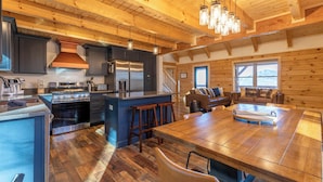 A spacious kitchen with a large island, stainless steel appliances, and a wooden ceiling. - Ursa Minor (Banner Elk)